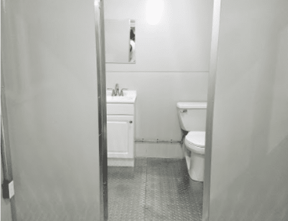 Open door showing toilet and sink with metal floor