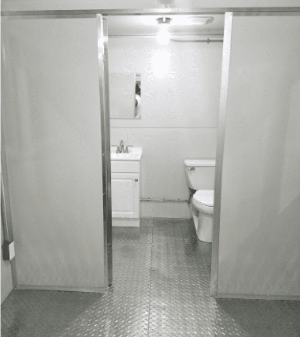 Open door showing toilet and sink with metal floor