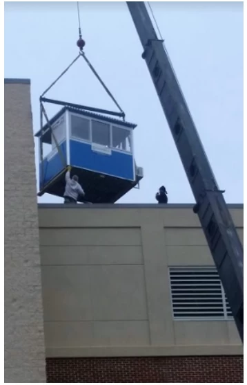 A blue office booth on a crane