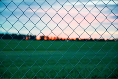 A chain link fence in front of a farm