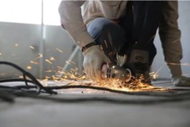 A construction worker using a power saw and making sparks