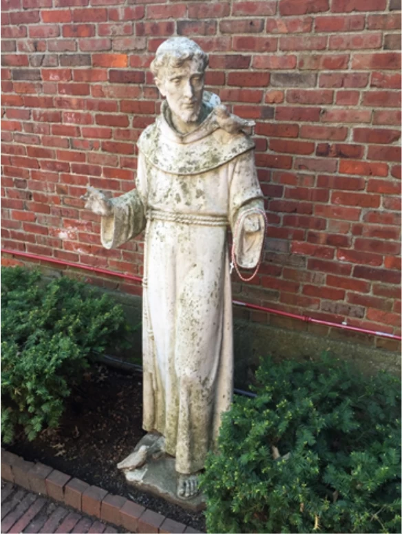 A religious statue of a man in front of a brick wall