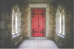 A stone hallway with a red door