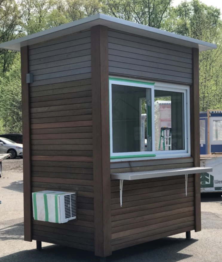 A ticket booth with brown slatted exterior and AC unit