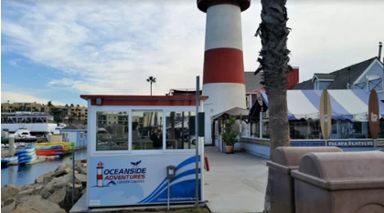 A white and red ticket booth with a lighthouse behind it