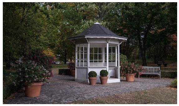 A white gazebo in a garden used as outdoor office shed
