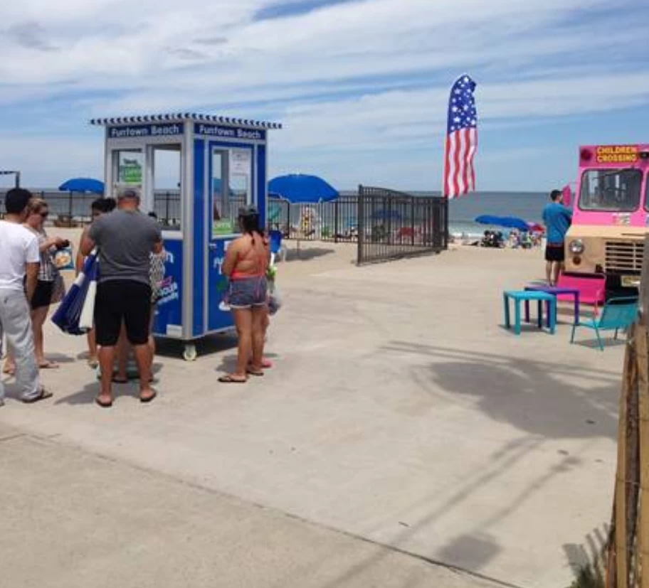 People standing around a blue booth at a beach