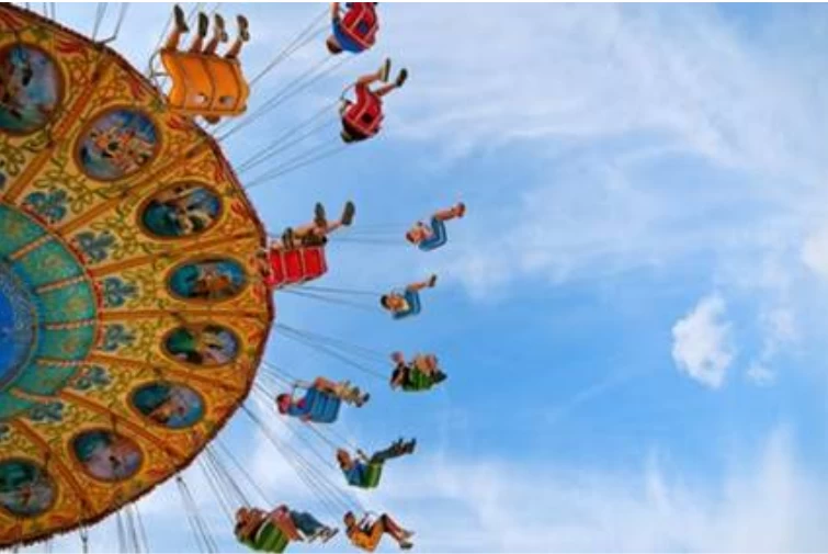 People riding a circular sky swing attraction at an amusement park - Maximize Profits in Amusement Park Management Systems