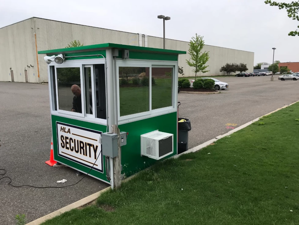 Green security booth with man running a cord to it