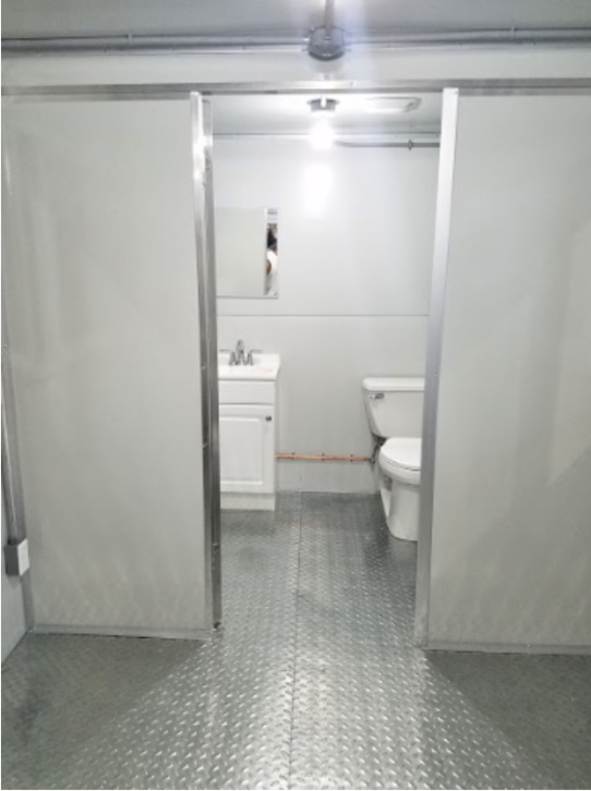 Open door showing toilet and sink with metal floor