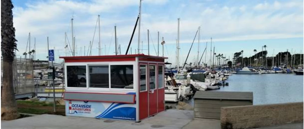 Red ticket booth design with Oceanside logo in front of marina