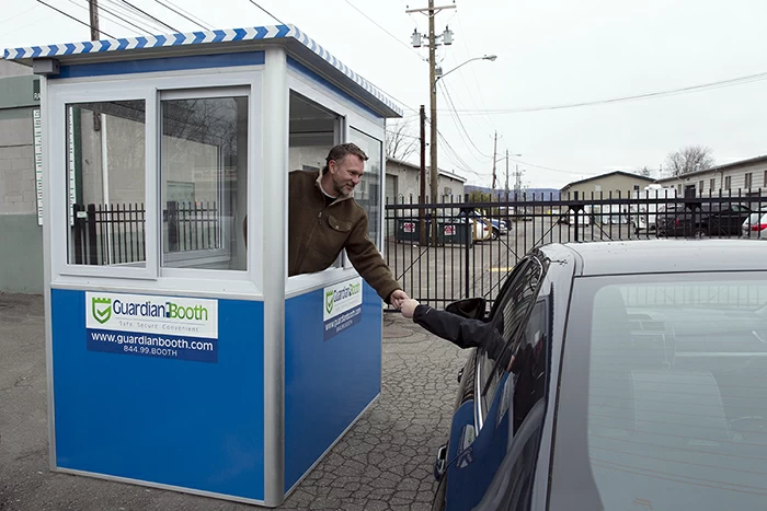 A man in a blue parking booth talking to a customer