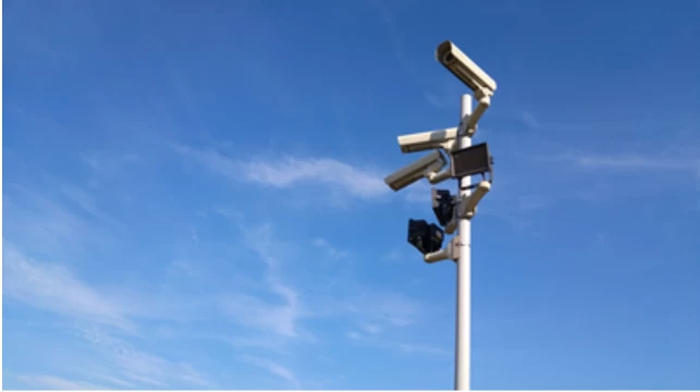 Security cameras mounted on a pole in front of blue sky
