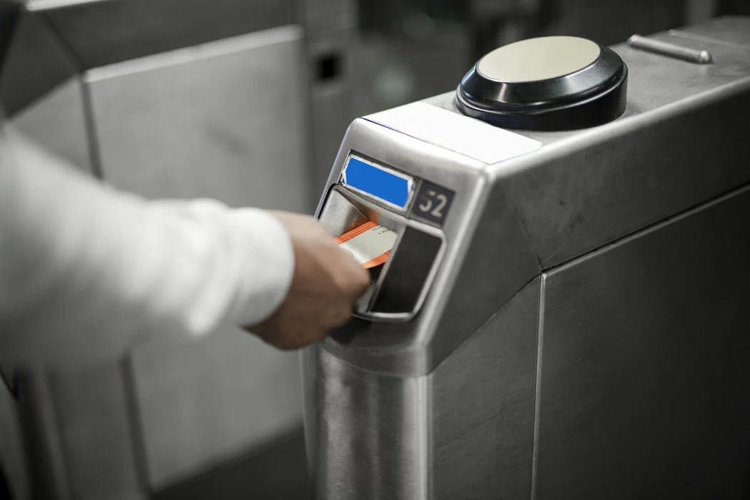 A hand using a card to activate a waist-high security turnstile
