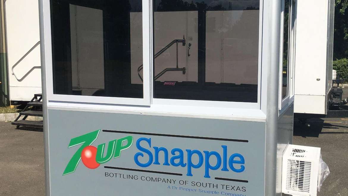 A-grey-prefabricated-security-guard-booth-branded-with-7Up-and-Snapple-logos